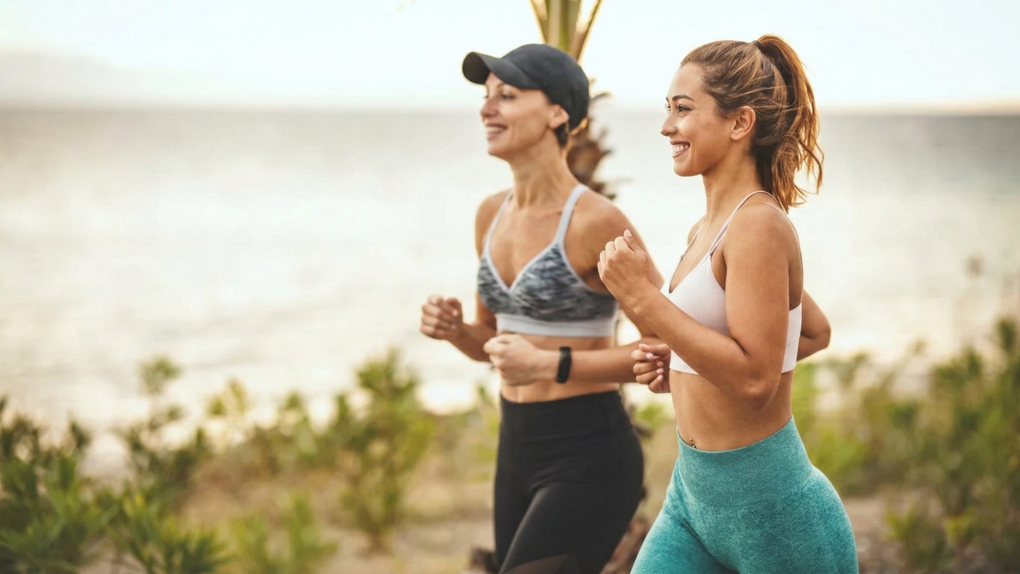 Two women walking outside by the sea are smiling