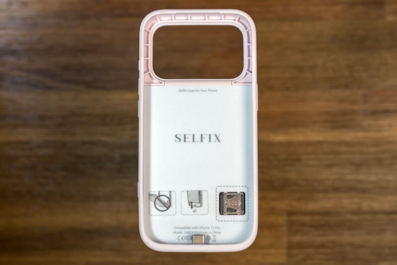 A pink and clear line of text "DONE ITSELF" it lies on a wooden surface, designed for the iPhone 7/8, with a large rectangular flow at the top and printed instructions visible on the back.