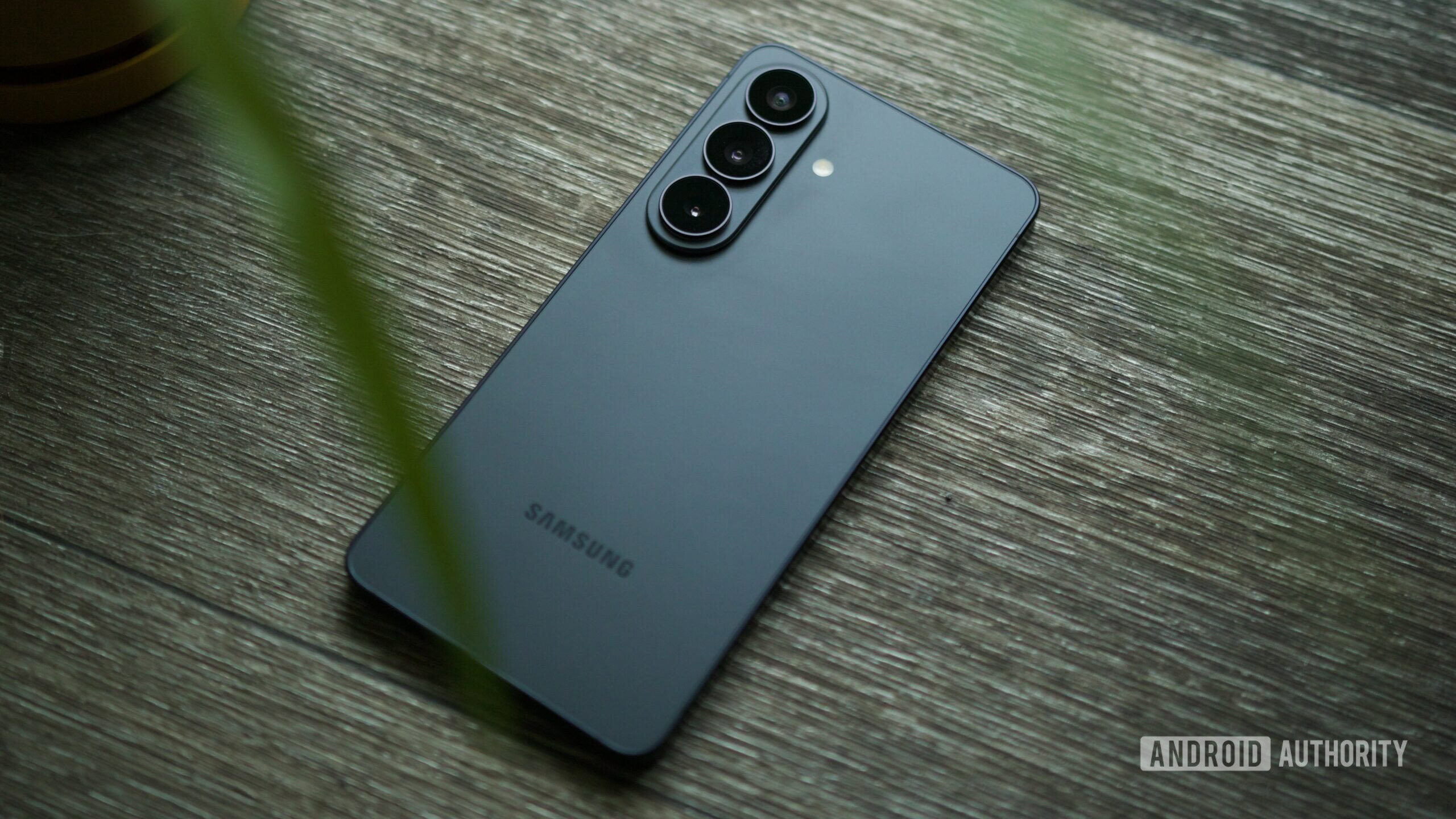 samsung galaxy s26 black back 1 Samsung Galaxy S26 placed on a wooden floor.