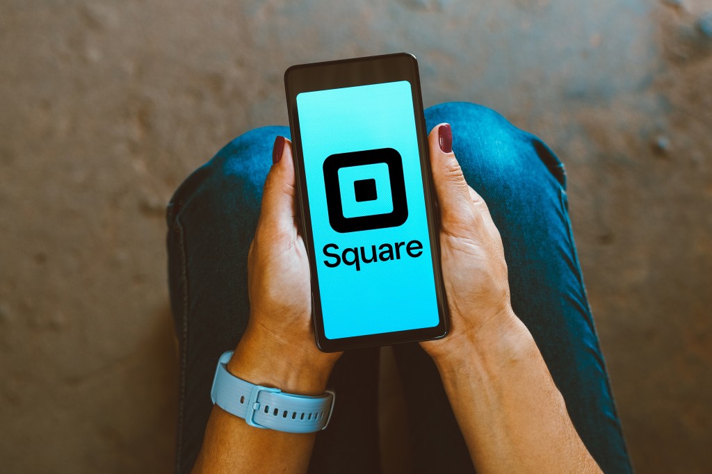 An image of a person holding a smartphone showing the Square logo.