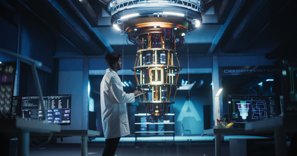 A scientist stands near quantum computing equipment in a lab.