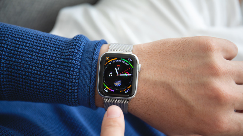 A man sitting in a blue shirt with a glowing Apple Watch display