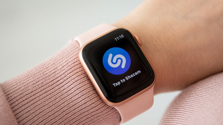 Apple Watch with a pink band on a woman's wrist showing the Shazam logo