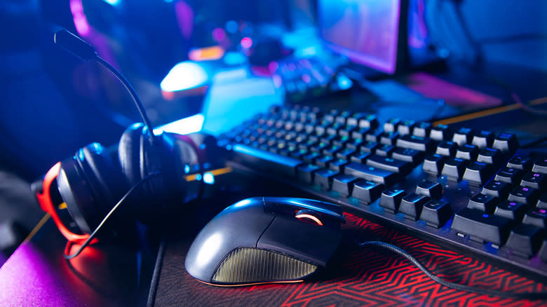 A headset, a computer mouse, and a computer keyboard sitting on a desk